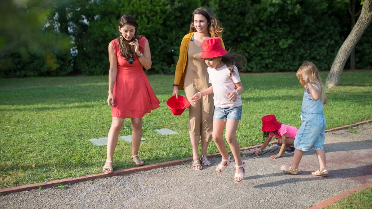 A joyous family experience in a lush Portugal park, featuring playful activities between young girls and adults.